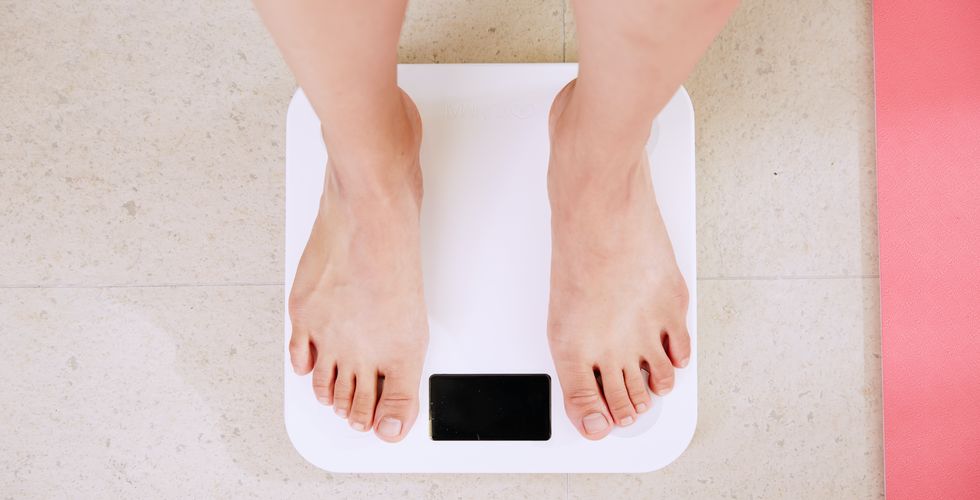Lady on a scale weighing herself to see if she is experiencing the same weight loss as others she has read in Saxenda reviews.